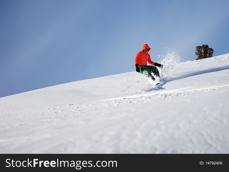 Snowboarder doing a toe side carve with deep blue sky in background