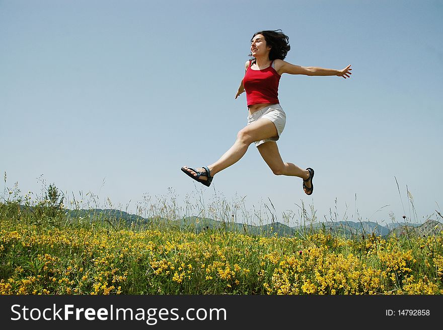 Beautiful young girl jumping on a yellow field