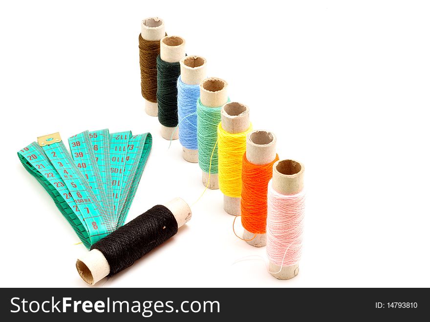 Colored spools of thread on white background