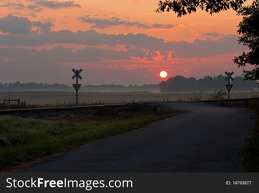 Rural sunrise with road and railroad crossing