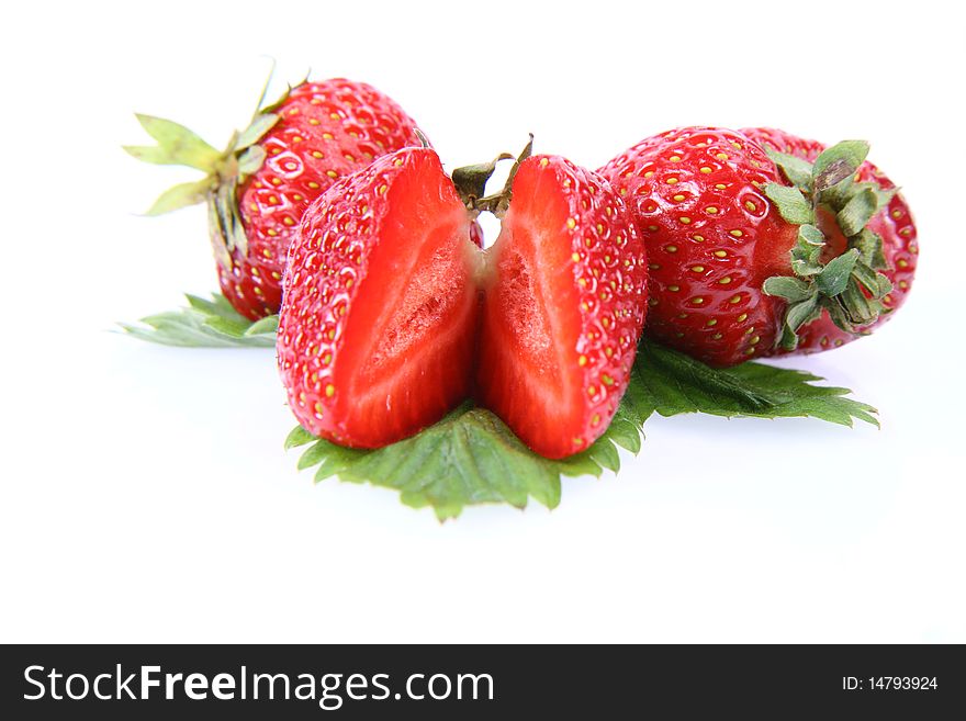 Strawberries on a leaf, one cut in half, on white background