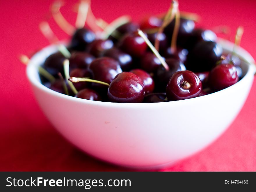 Cup with cherries on red background