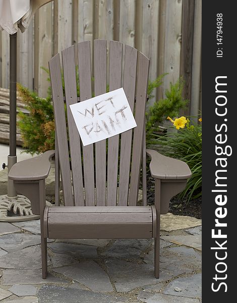 A wet paint sign on a freshly painted wood chair outdoors on a patio. A wet paint sign on a freshly painted wood chair outdoors on a patio