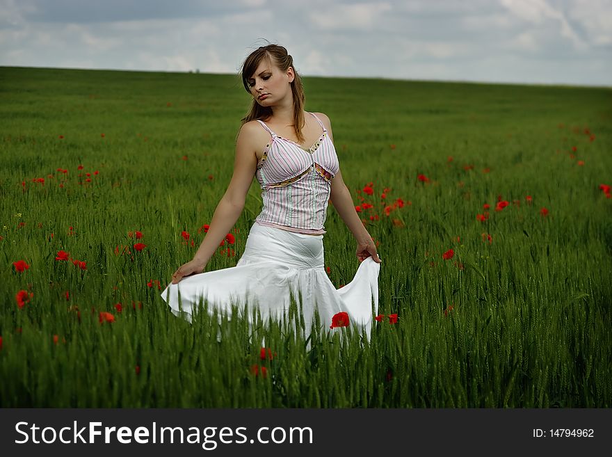Beautiful young woman standing on the poppy's field. Beautiful young woman standing on the poppy's field