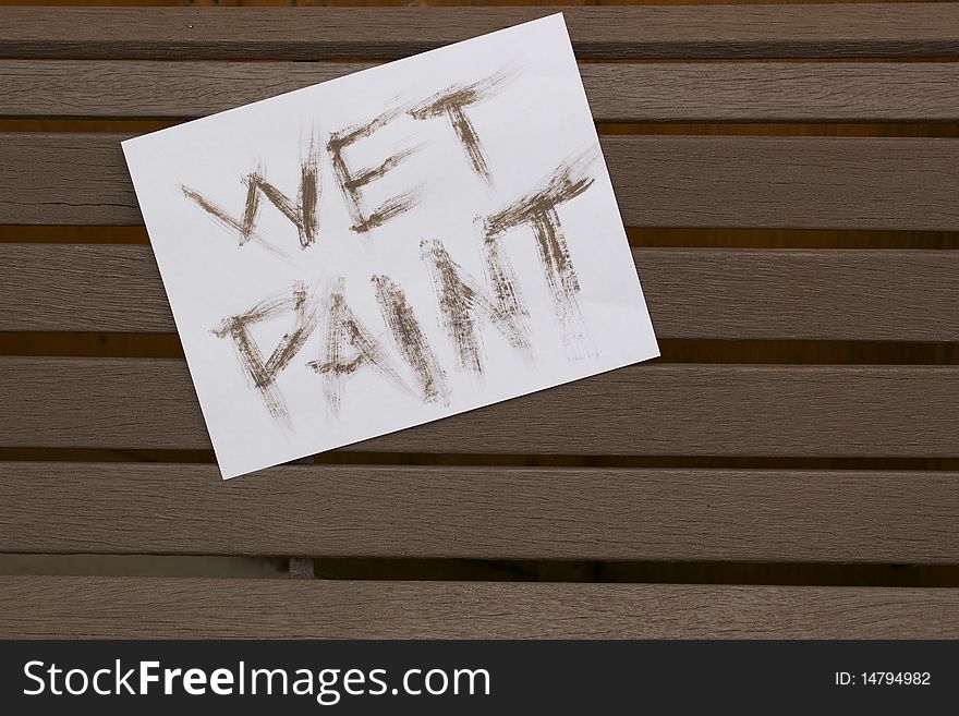 A wet paint sign on a freshly painted wooden bench