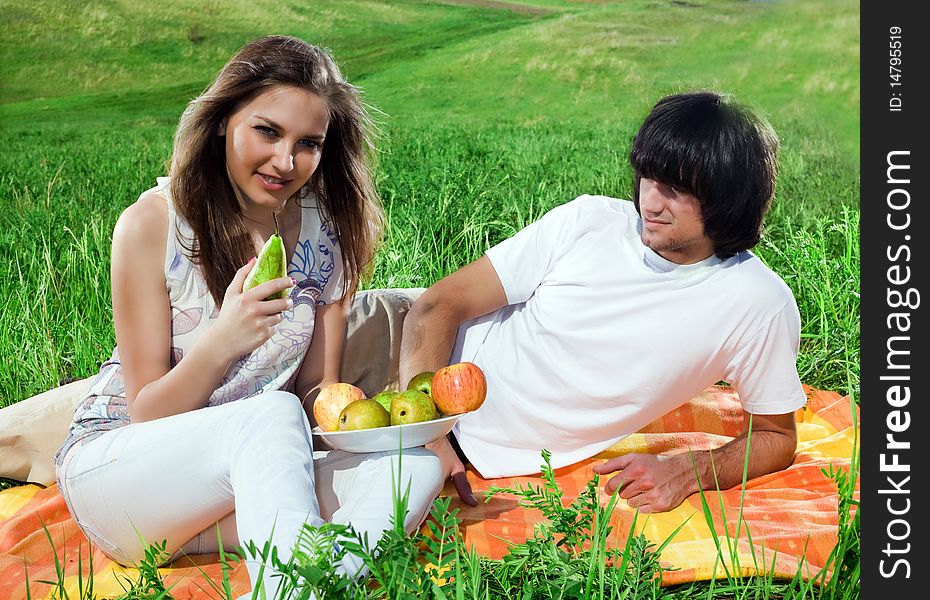 Long-haired girl with fruits and boy on grass
