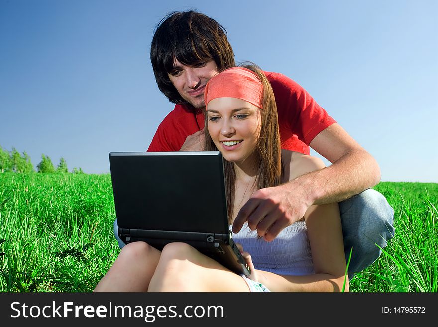 Long-haired girl with notebook and boy with smile on grass. Long-haired girl with notebook and boy with smile on grass