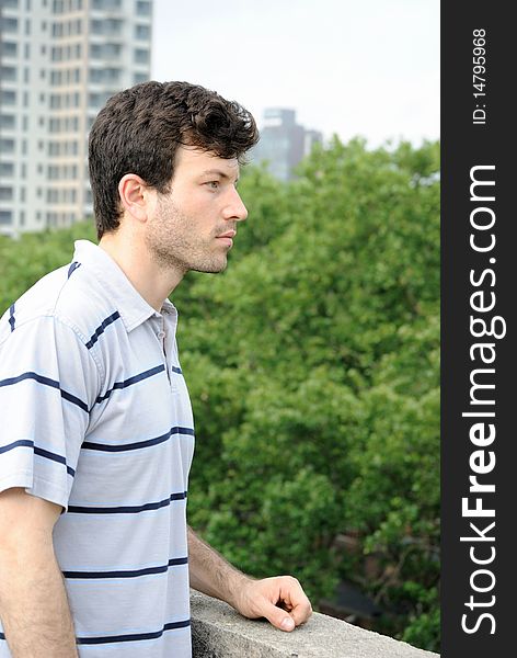 A man staring over a city rooftop with a park behind. A man staring over a city rooftop with a park behind.