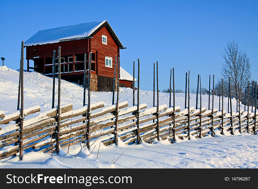 Old red house in the winter with an old fence in front. Old red house in the winter with an old fence in front.