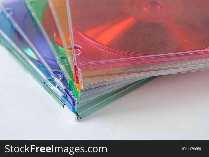 Multicolored cd jewel cases stacked on white.