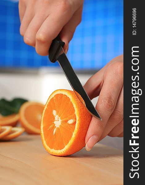 Female chopping juicy orange on the kitchen. Female chopping juicy orange on the kitchen.