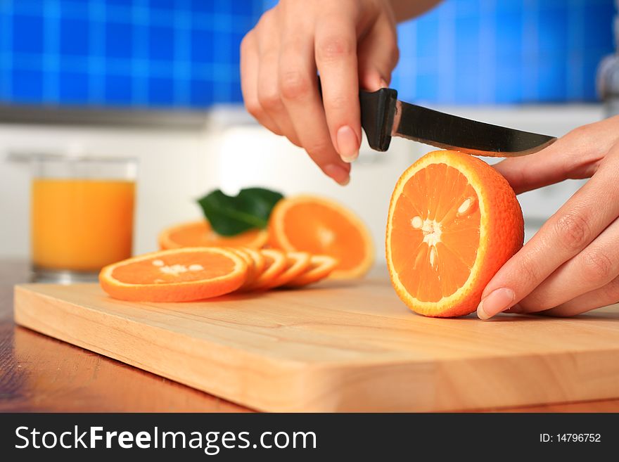 Female chopping juicy orange on the kitchen. Female chopping juicy orange on the kitchen.