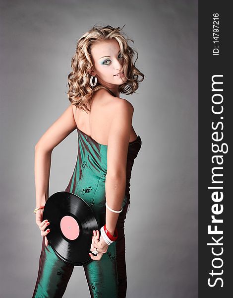 Beautiful girl in trend clothes holding vinyl disc in her hands looking at the photographer.