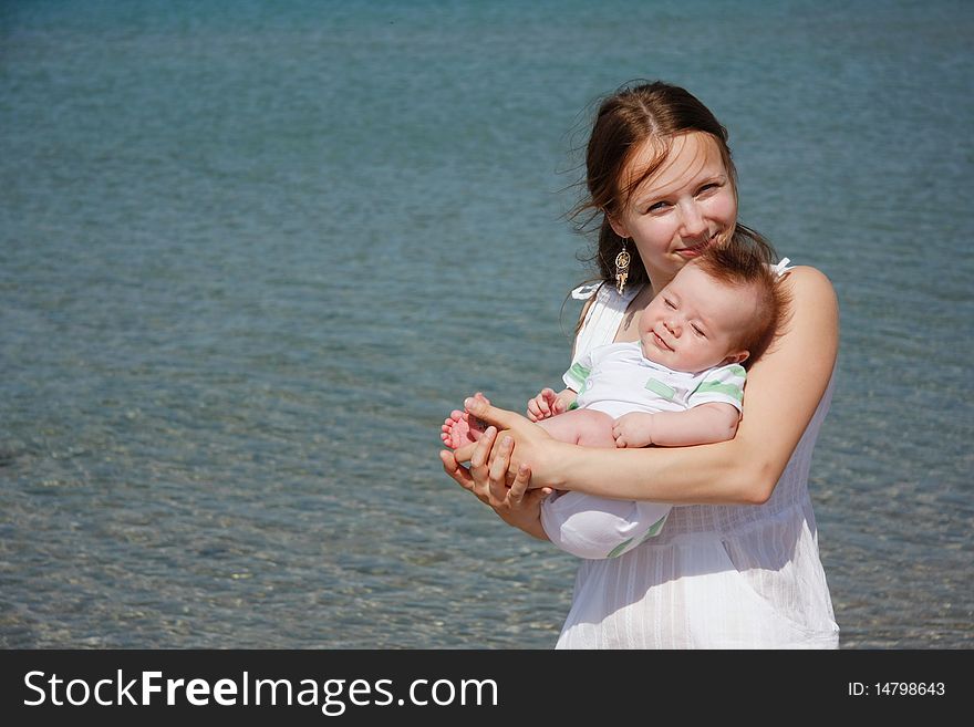 Young mother and baby on sea background