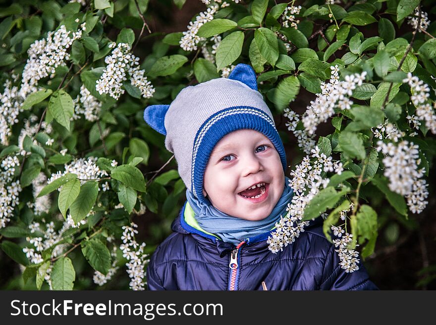 Child near blooming tree, happy face in nature