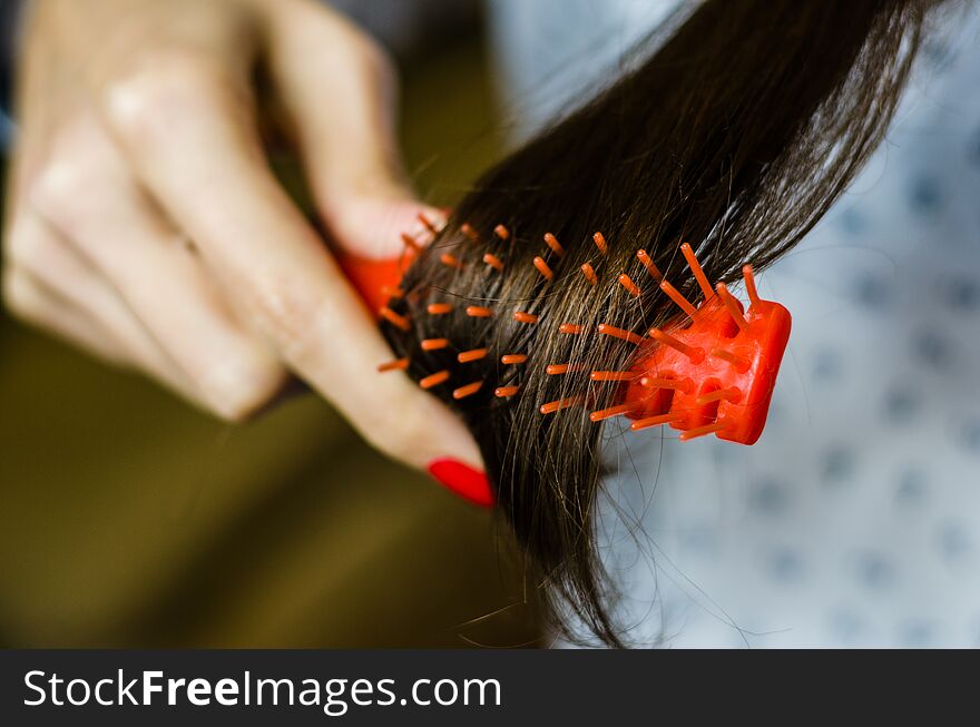 Young brunette woman combing her brown hair. Selective focus