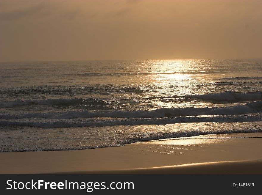 Sun rising over tropical beach with a light orange glow. Sun rising over tropical beach with a light orange glow