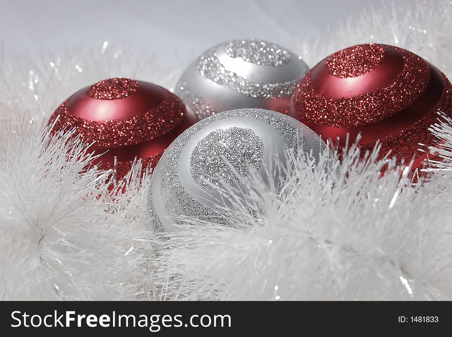 Four oranamnets in white tinsel.  Ornaments are red and silver with glitter in a swirl pattern. Four oranamnets in white tinsel.  Ornaments are red and silver with glitter in a swirl pattern.