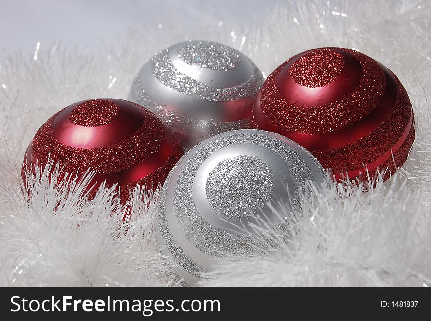 Four oranamnets in white tinsel. Ornaments are red and silver with glitter in a swirl pattern. Four oranamnets in white tinsel. Ornaments are red and silver with glitter in a swirl pattern.