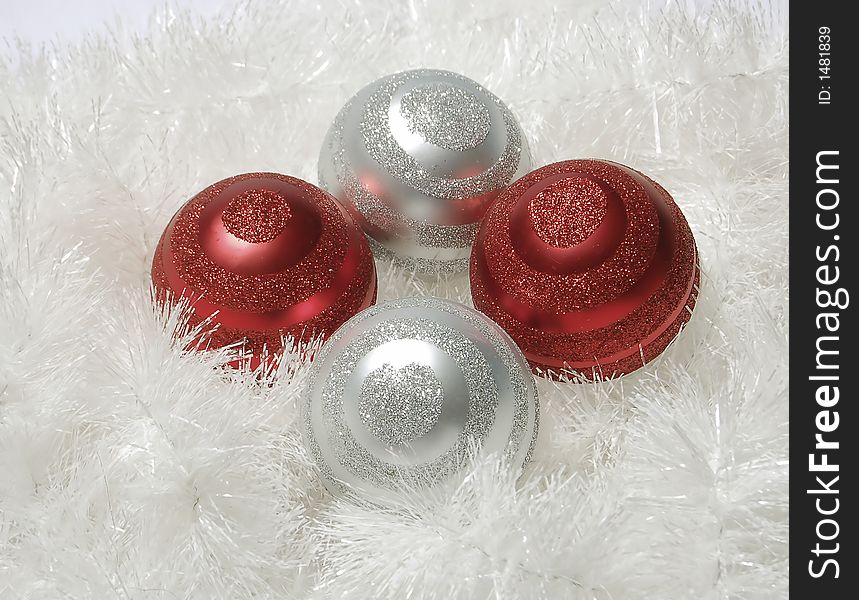 Four ornaments in white tinsel. Ornaments are red and silver with glitter in a swirl pattern. Four ornaments in white tinsel. Ornaments are red and silver with glitter in a swirl pattern.