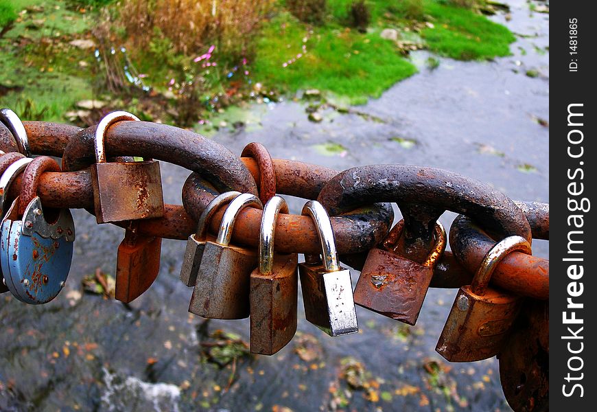 Sealed padlocks closed to heavy chain over river. Sealed padlocks closed to heavy chain over river