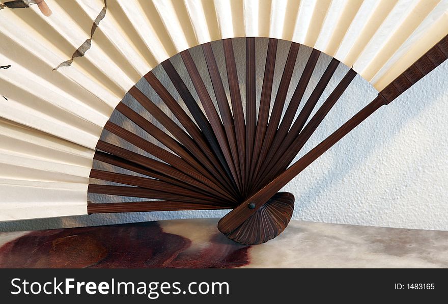 White, Beige Decorative Fan With Wood Grip On A Marble Table