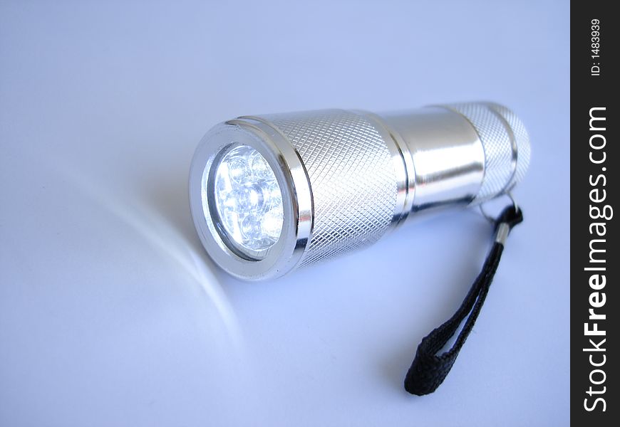 Silver metallic flashlight on blue background