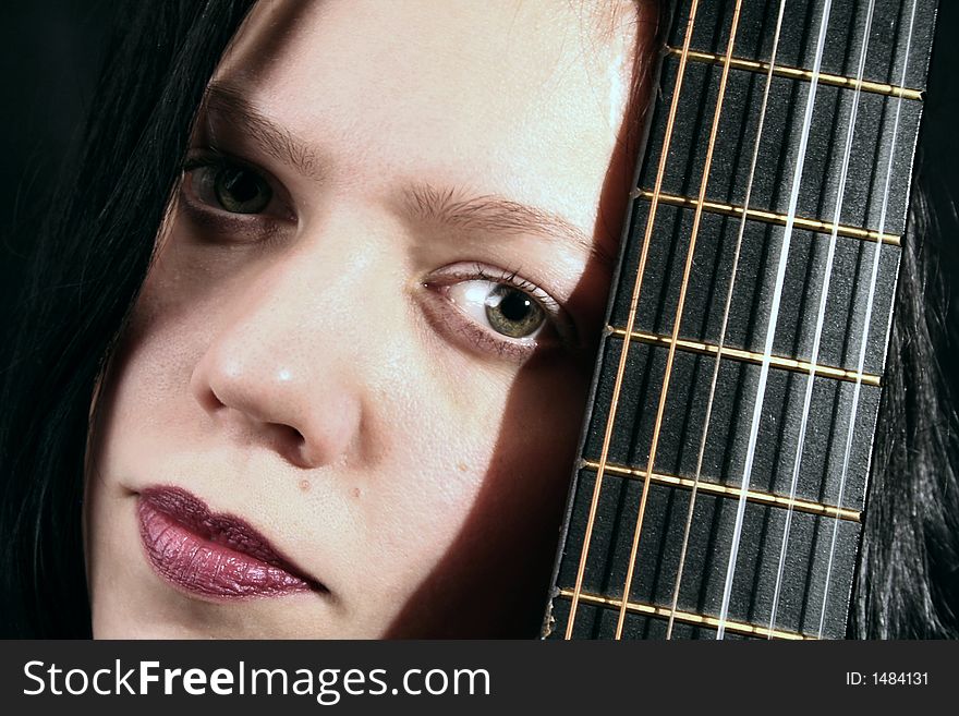 Young woman with part of a guitar in the dark. Young woman with part of a guitar in the dark