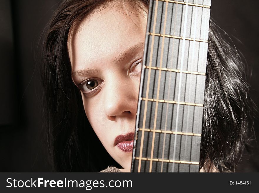 Young woman with part of a guitar in the dark. Young woman with part of a guitar in the dark