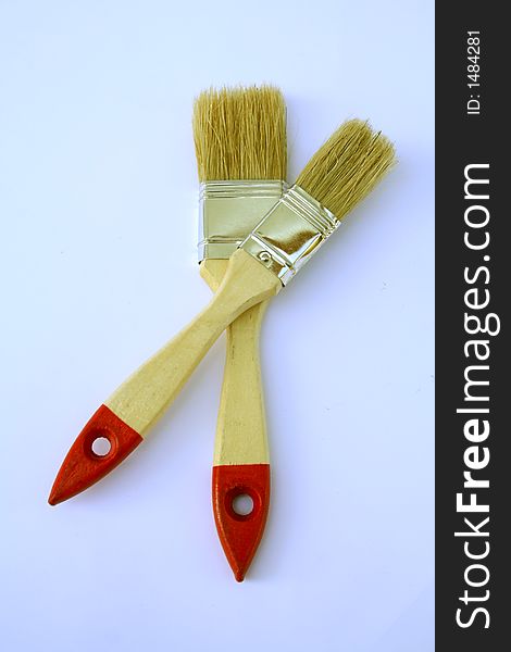 Two painting brushes with red handles on a paper