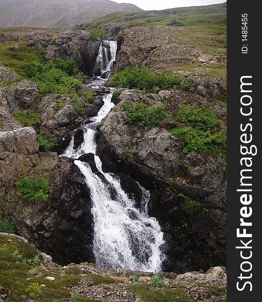 Alpine waterfall gushing down rock crevice in alaska