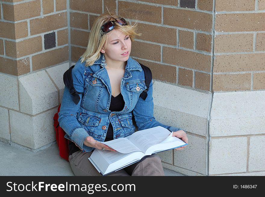 Beautiful young woman studying by a school. Beautiful young woman studying by a school.