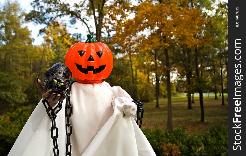 A pumpkin, jack-o-lanten headed Halloween doll made up to look like a ghost. A pumpkin, jack-o-lanten headed Halloween doll made up to look like a ghost.