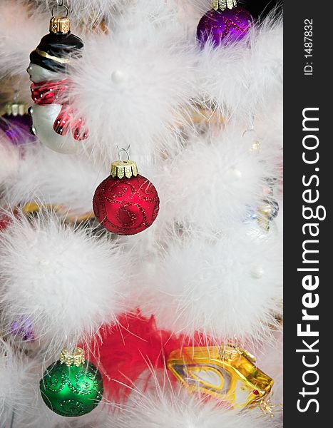 Christmas ornaments hanging on a white feather tree.