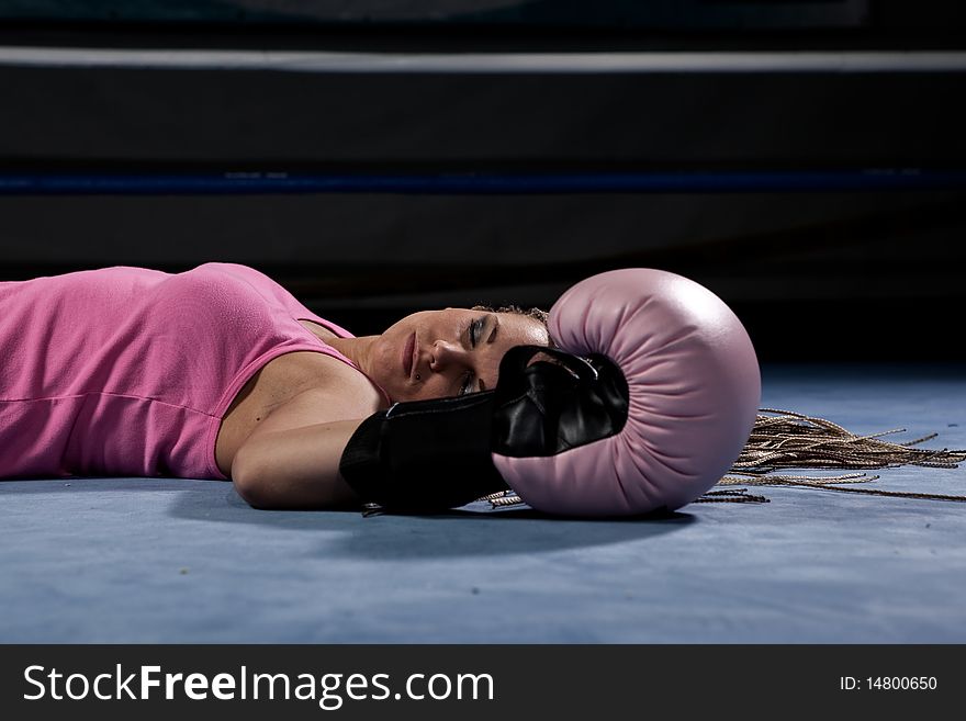 Blonde girl lying knocked out in a boxing ring. Blonde girl lying knocked out in a boxing ring