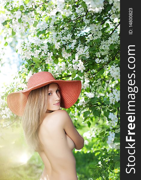 Beautiful half-naked woman among flowering gardens