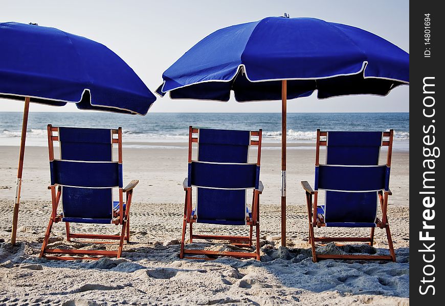 Three beach chairs and two umbrellas on sunny day at the beach