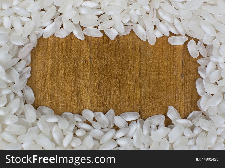 Frame of uncooked rice on wooden background  with copy space.