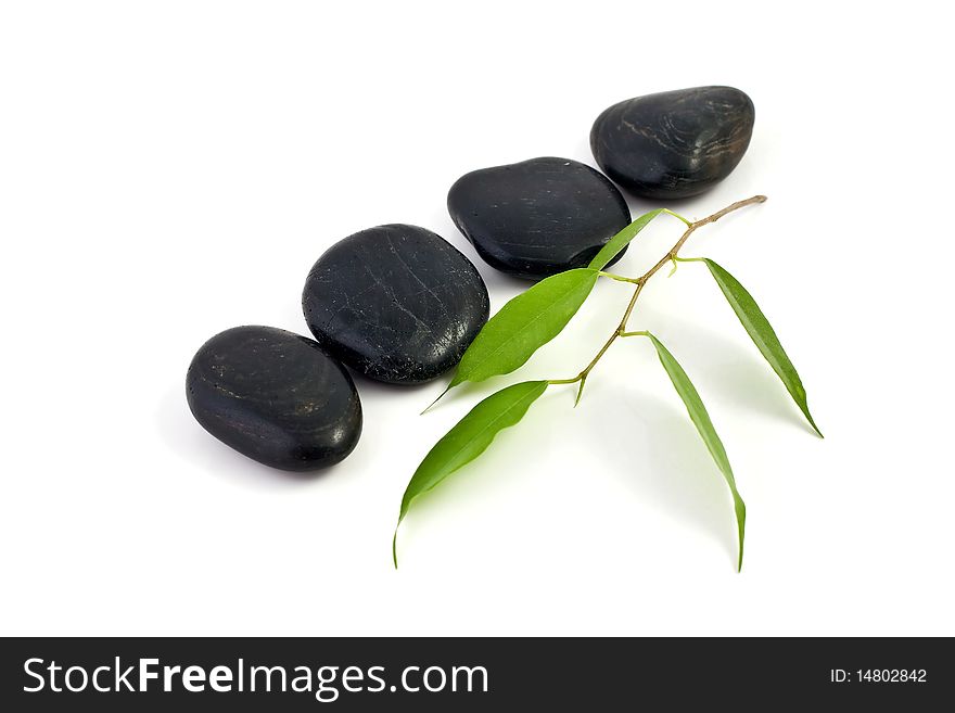 An image of four black stones and green leaves. An image of four black stones and green leaves