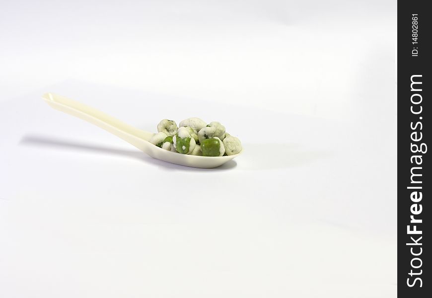 A spoonful of green peas fried to make a party snack. A spoonful of green peas fried to make a party snack.