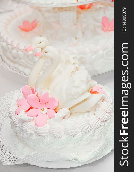 A piece of a beautiful wedding cake with two swans and flowers