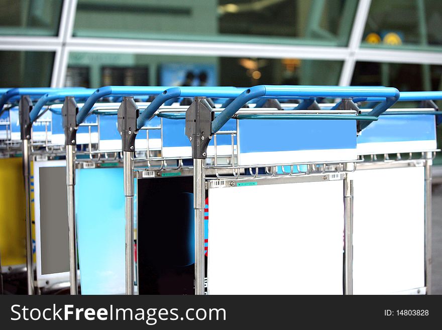 Row of luggage carts at busy airport, with selective focus on the closer carts