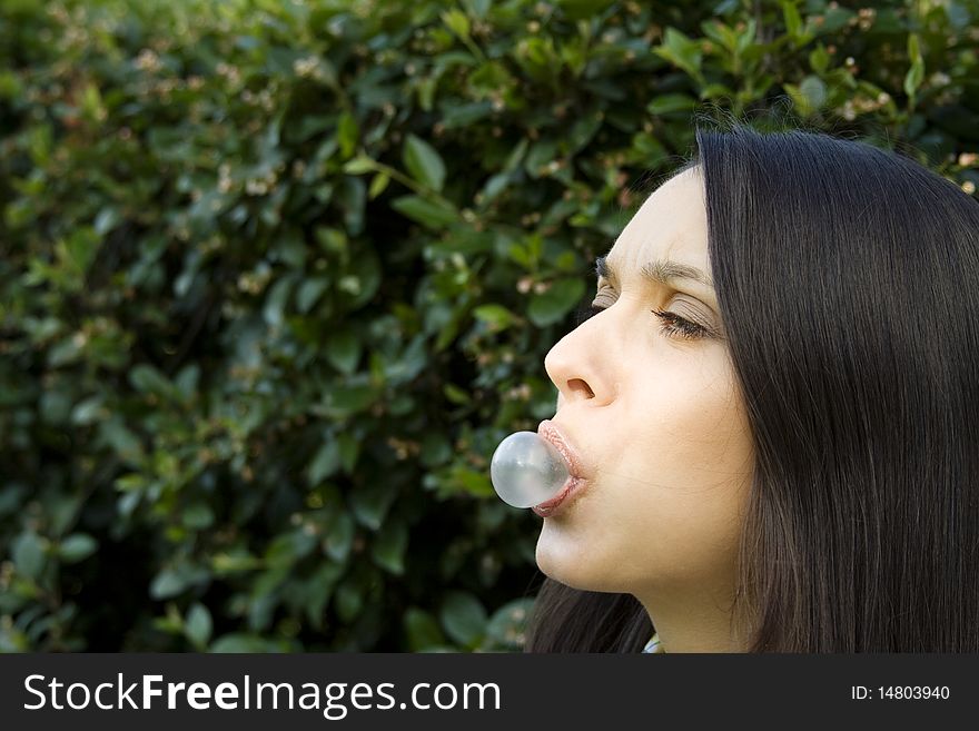 Girl in a park on the green background of foliage, blowing a bubble. Girl in a park on the green background of foliage, blowing a bubble