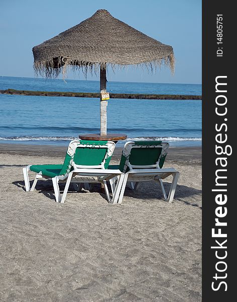 Two empty beach chairs and umbrella. Atlantic Ocean coast, Canary Islands. Two empty beach chairs and umbrella. Atlantic Ocean coast, Canary Islands