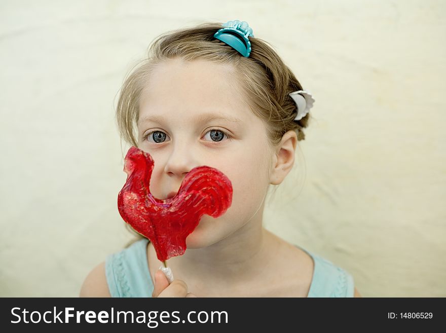 An image of a little girl with sweet red candy. An image of a little girl with sweet red candy