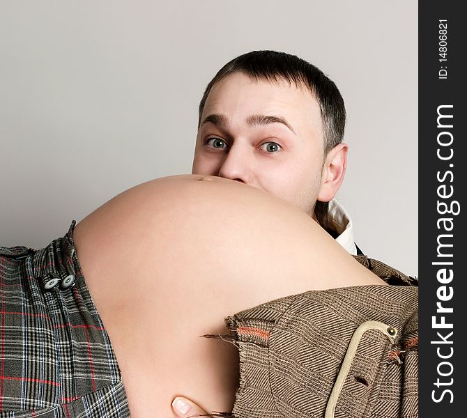An image of a man kissing his pregnant wife's belly. An image of a man kissing his pregnant wife's belly