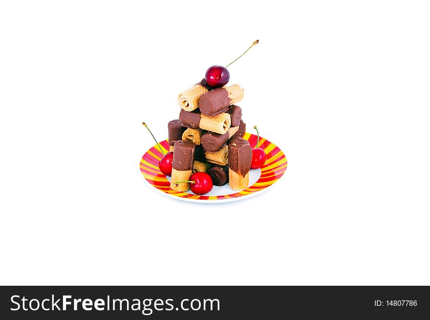 Sweet chocolate puffs bright  plate and cherries isolated on white. Sweet chocolate puffs bright  plate and cherries isolated on white
