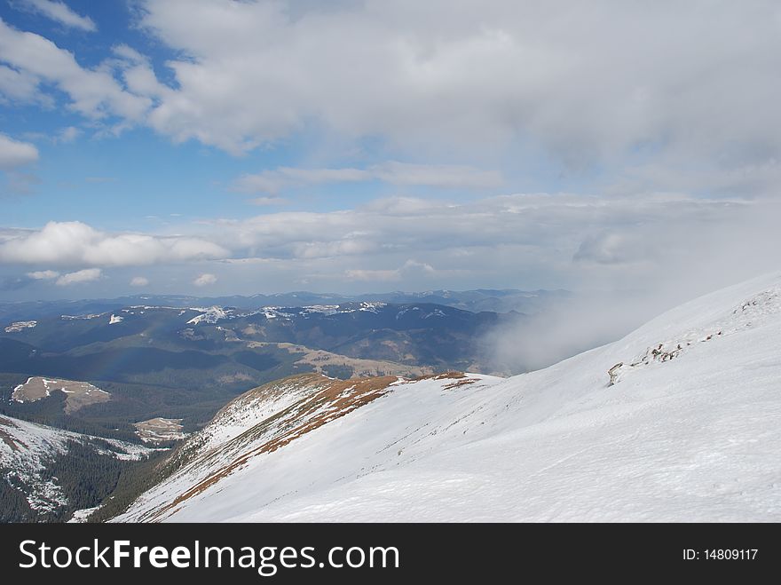 A mountain winter slope in clouds in a landscape with white snow. A mountain winter slope in clouds in a landscape with white snow