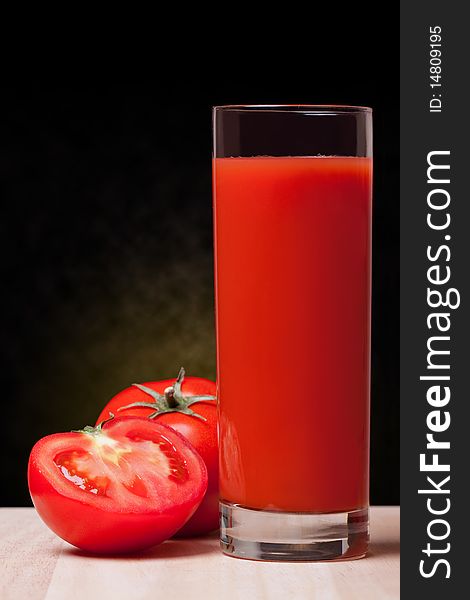 Fresh tomatoes and a glass full of tomato juice.