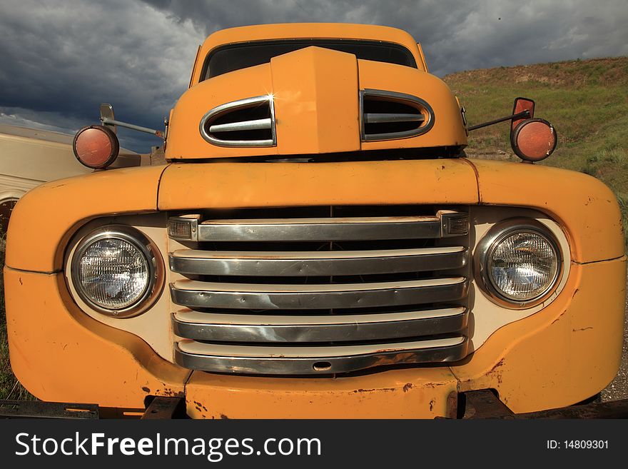 Old yellow pickup truck with clouds